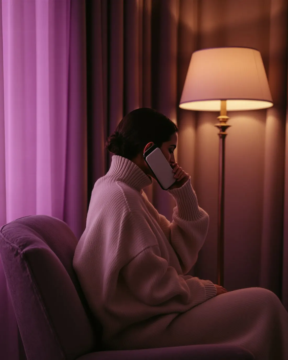 Una donna in penombra lilla, il telefono tenuto vicino e privato tra le mani